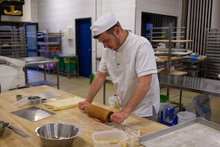 Martin Walther beim Arbeiten mit der Teigrolle während der Prüfung in der Backstube der ADB